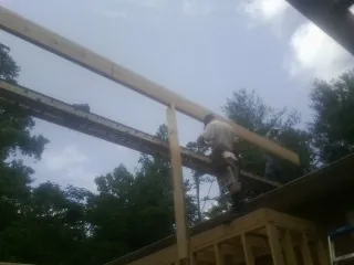Carpenter setting a ridge beam over a new addition frame — Ice Dam Removal by Roofing Brothers in Greenhurst