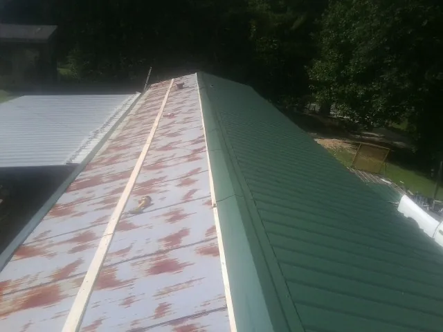 Old rusted panels beside newly installed green metal roofing — Wind Damage Roof Repair by Roofing Brothers in Greenhurst