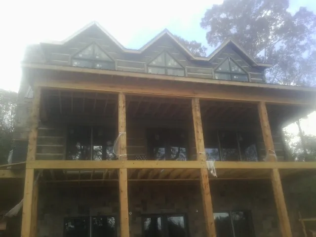 Dormers and porch framing on a large log home under construction — Roof Coating work by our crew in Greenhurst