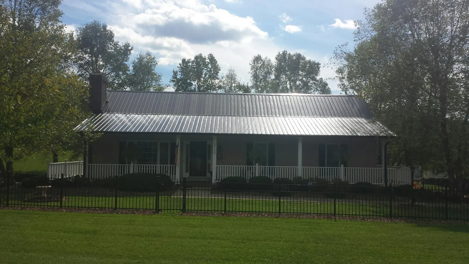 Gray metal roof on a brick ranch with a full width front porch — Gutter Guard Installation work by our crew in Greenhurst