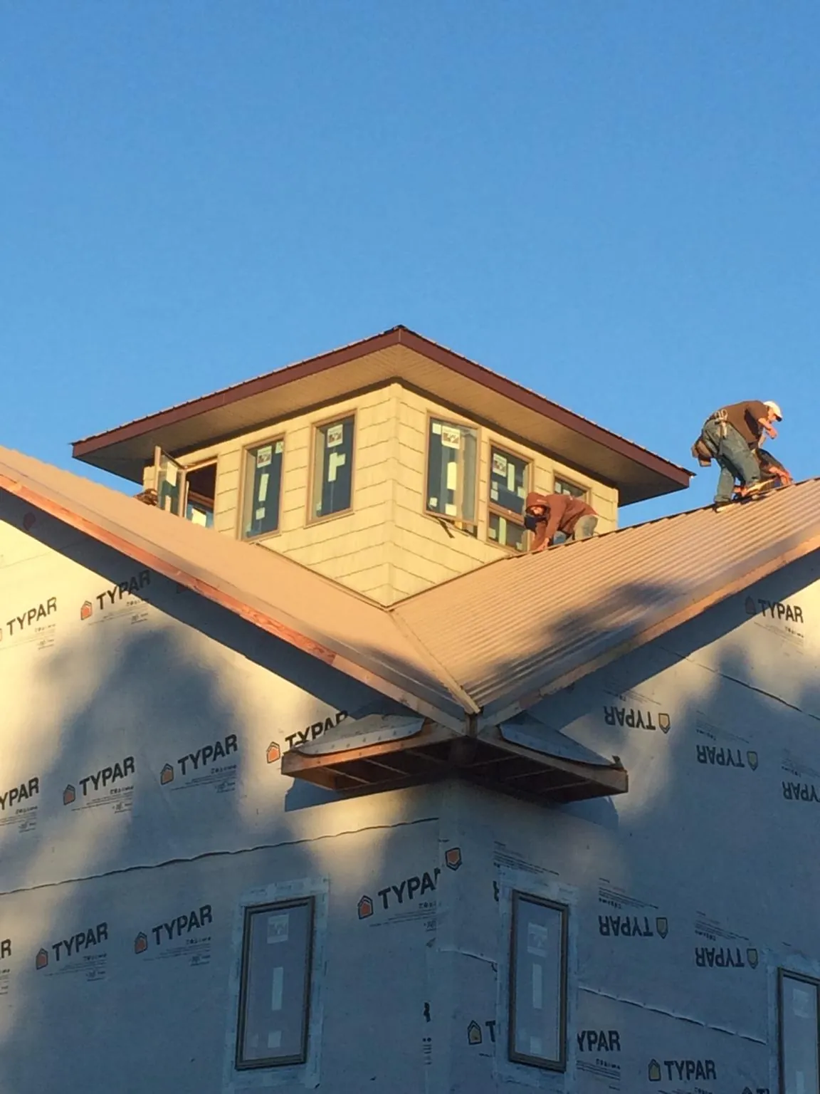 Roofers working around a rooftop cupola on a new metal roof at sunset — Roof Waterproofing in Greenhurst by Roofing Brothers